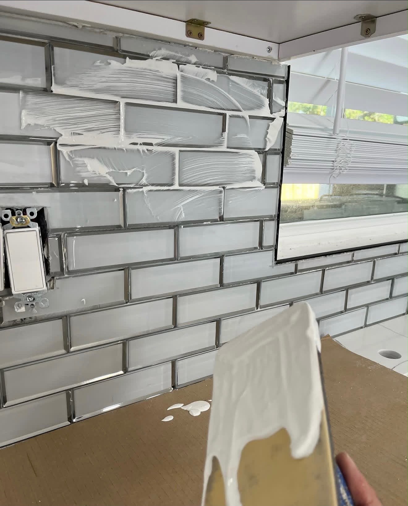 Finished glass subway tile backsplash around the kitchen window
