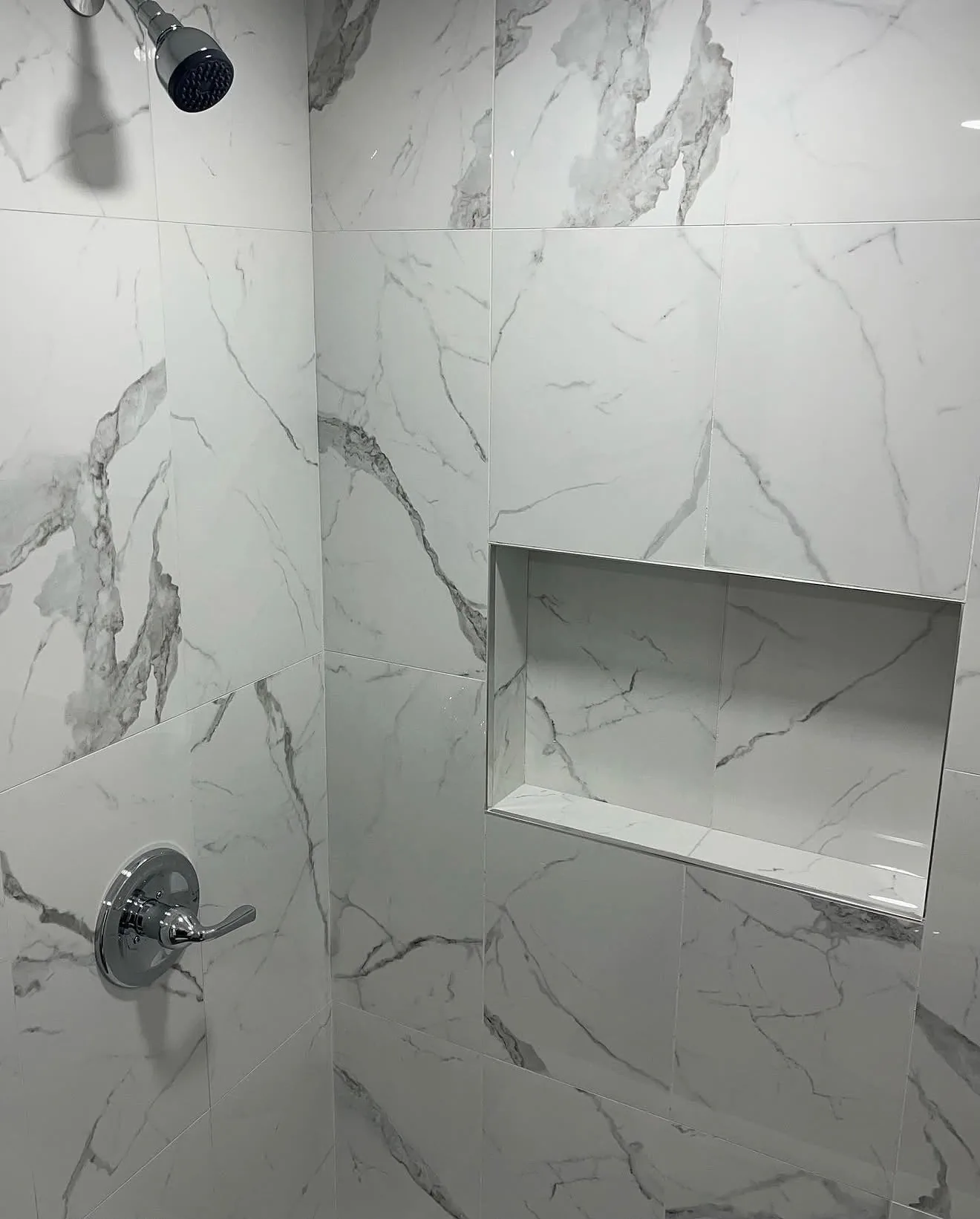 Chrome shower fixtures on marble-look tile
