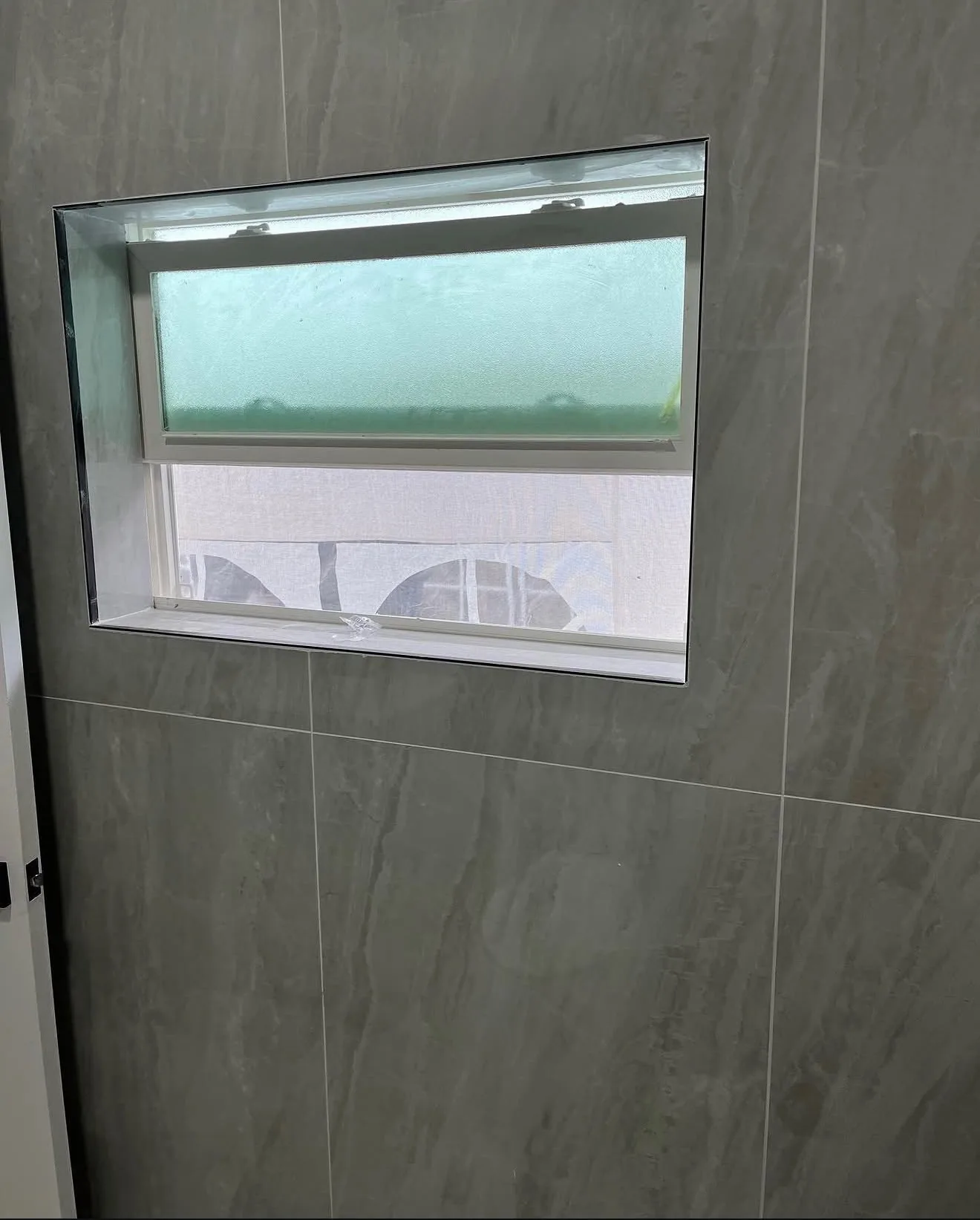Tiled window return in gray stone-look porcelain inside the shower