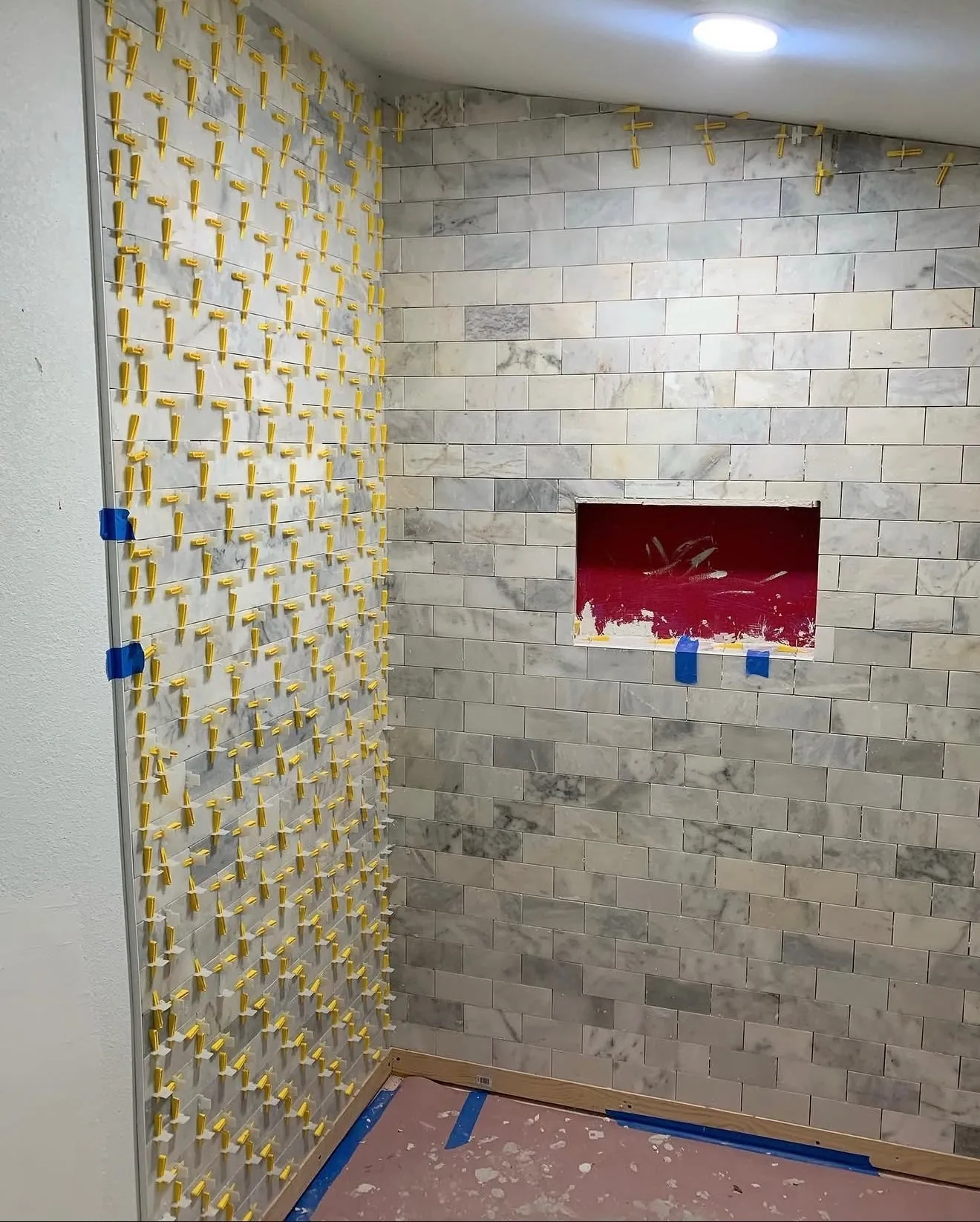 Close-up of marble subway tile set with leveling clips on shower wall