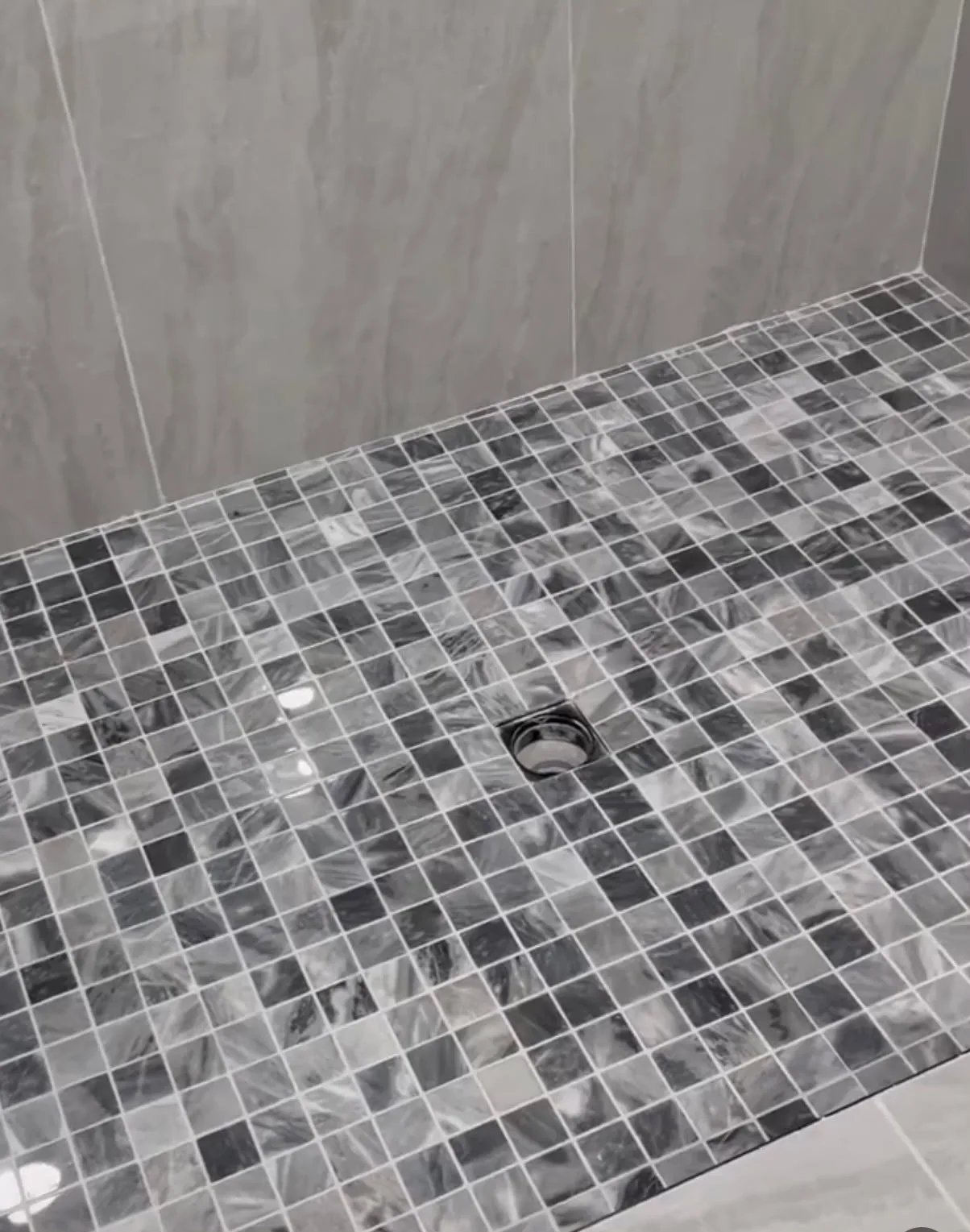 Black-and-gray glass mosaic shower floor with centered drain