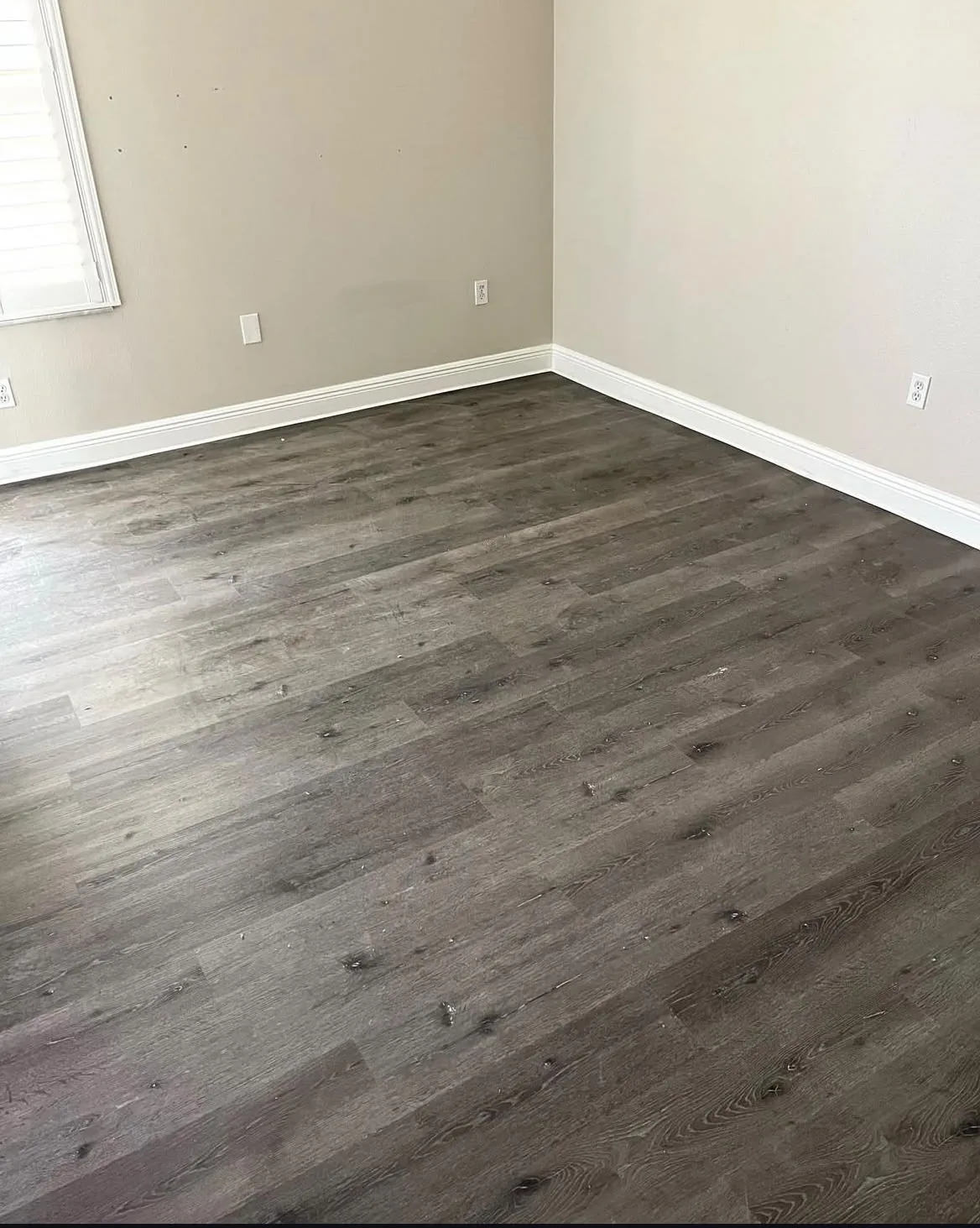 Wide view of finished gray vinyl plank flooring room corner