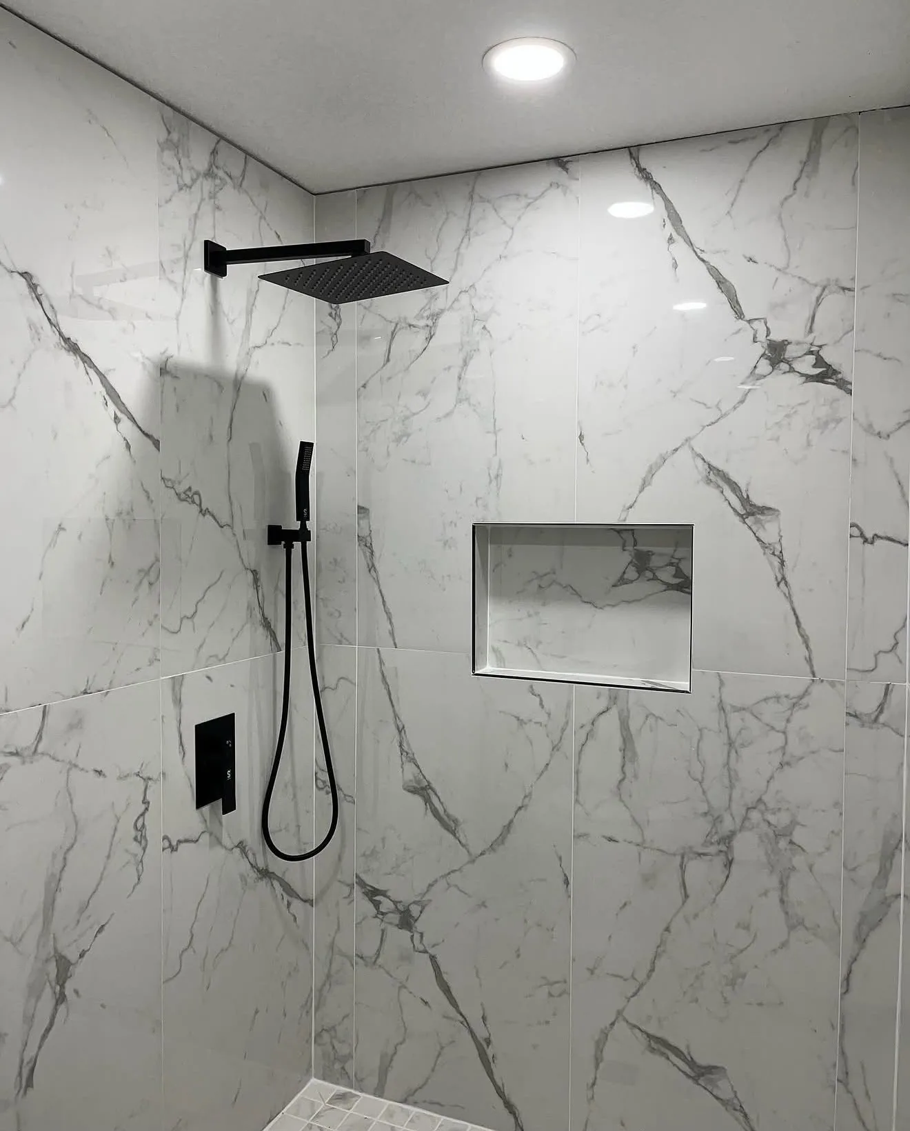 Finished white marble-look walk-in shower with recessed niche