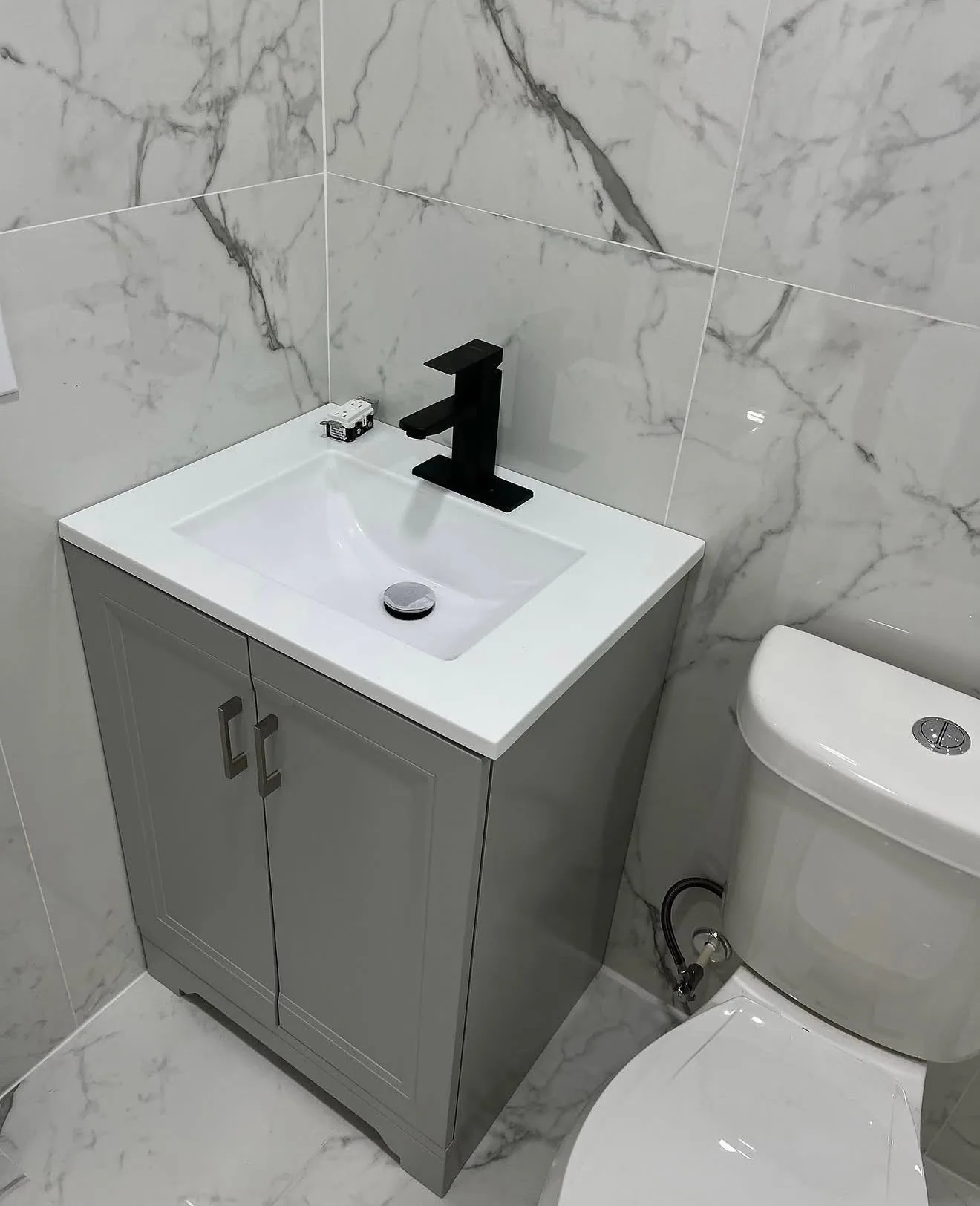 White marble-look vanity with black faucet and gray cabinet