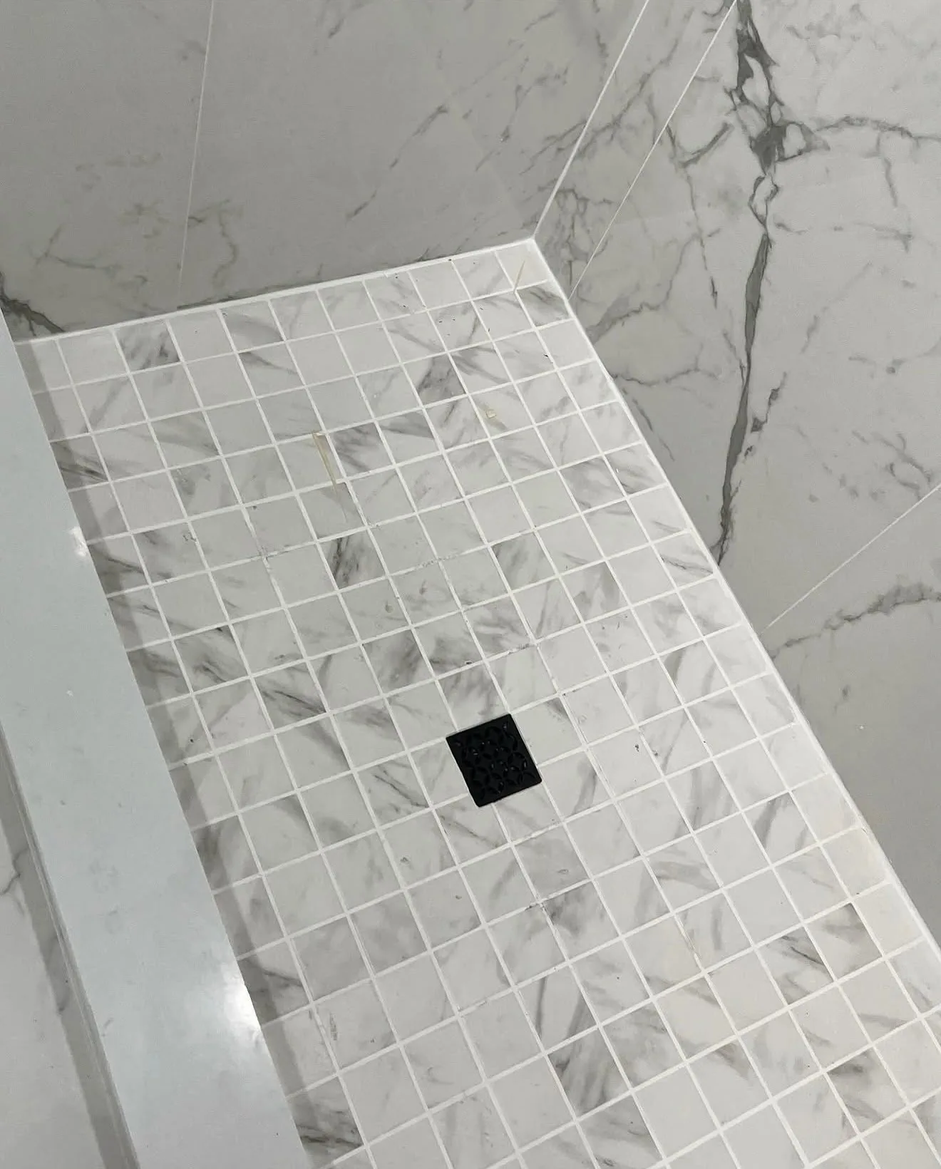 White marble mosaic shower floor with matte black drain